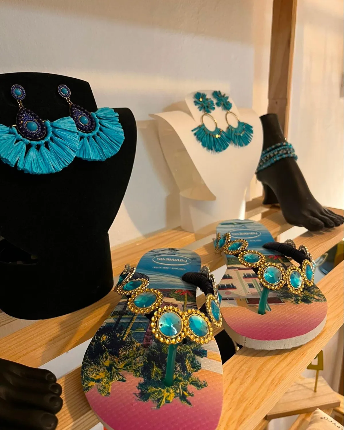 Boucles d’oreilles en raphia turquoise, bracelet de cheville et sandales ornées, présentés en boutique à Jarry